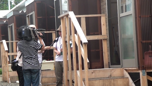 2011年福島の応急仮設住宅を訪問した際、テレビのインタビューに応える石井。