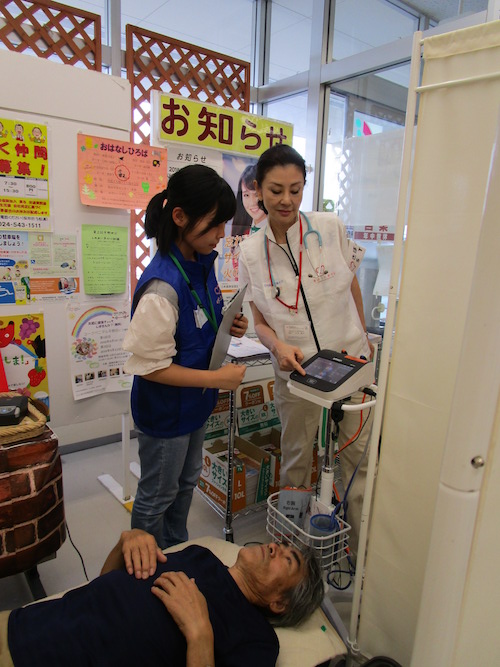 「血圧脈波測定」を実施している石井と学生ボランティア