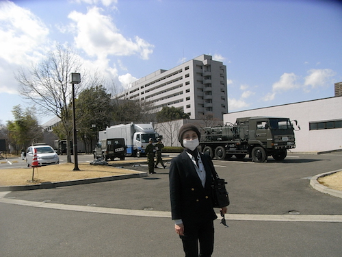 福島県立医科大学附属病院前にて石井。後方に救援活動をする自衛隊の車