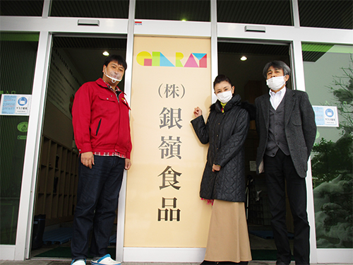 ㈱銀嶺食品訪問の記念に本社入り口で、社長の岡崎さん（左）と取締役の齋藤さんと記念撮影。3人とも真剣なちょっと硬い表情です